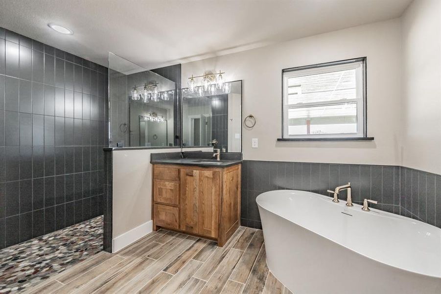 Full bath with vanity, a wainscoted wall, a freestanding bath, walk in shower, and wood finish floors Full bath with vanity, a wainscoted wall, a freestanding bath, walk in shower, and wood finish floors