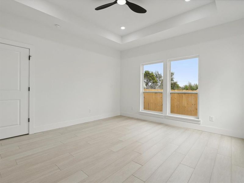 Unfurnished room with ceiling fan, light hardwood / wood-style floors, and a raised ceiling