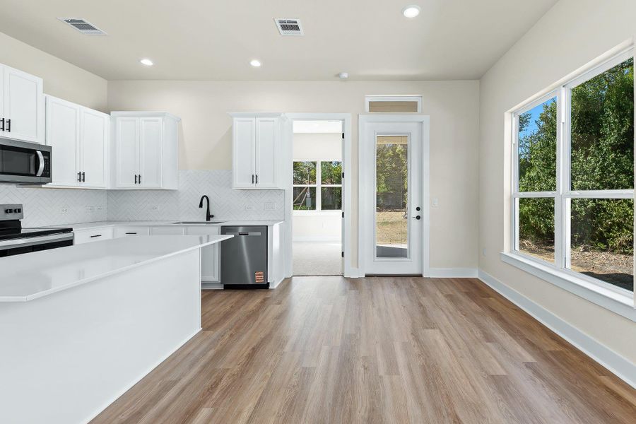 Kitchen featuring white cabinetry, decorative backsplash, appliances with stainless steel finishes, light wood finished floors, and recessed lighting