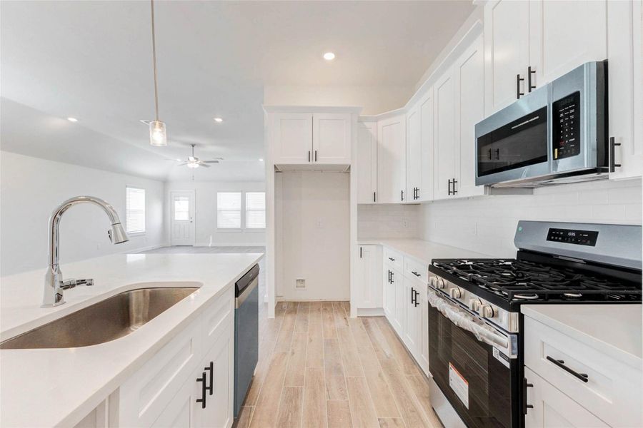 Cook, prep, and gather around the oversized island with seating space and overhead pendant lighting. Modern shaker cabinetry, black hardware, and stainless steel gas appliances add flair and function to this perfectly planned kitchen hub at the heart of the home. Cook, prep, and gather around the oversized island with seating space and overhead pendant lighting. Modern shaker cabinetry, black hardware, and stainless steel gas appliances add flair and function to this perfectly planned kitchen hub at the heart of the home.