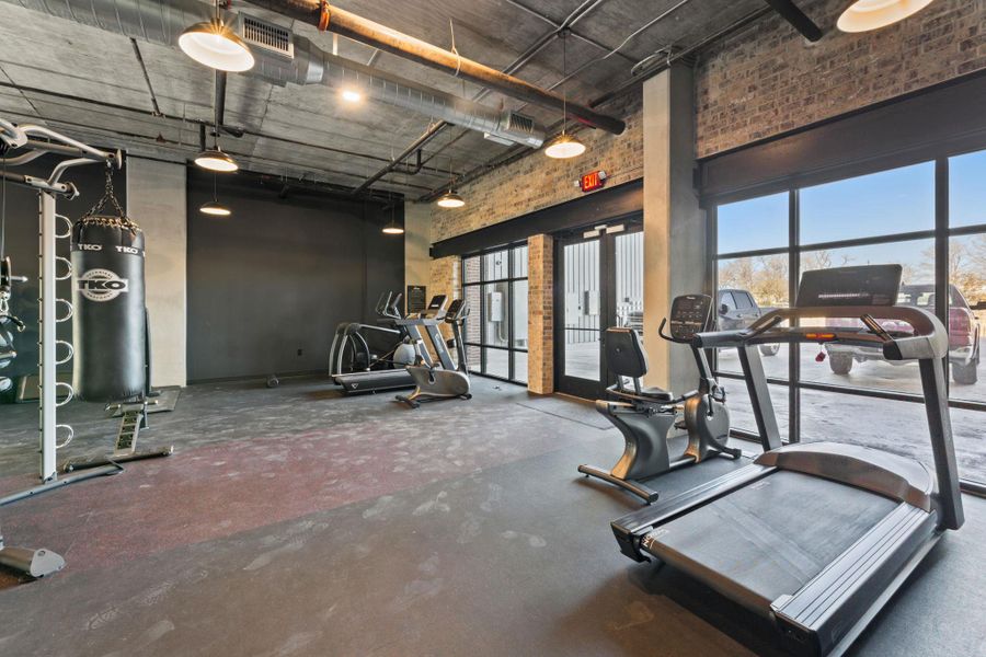 Exercise room featuring a high ceiling, brick wall, and french doors