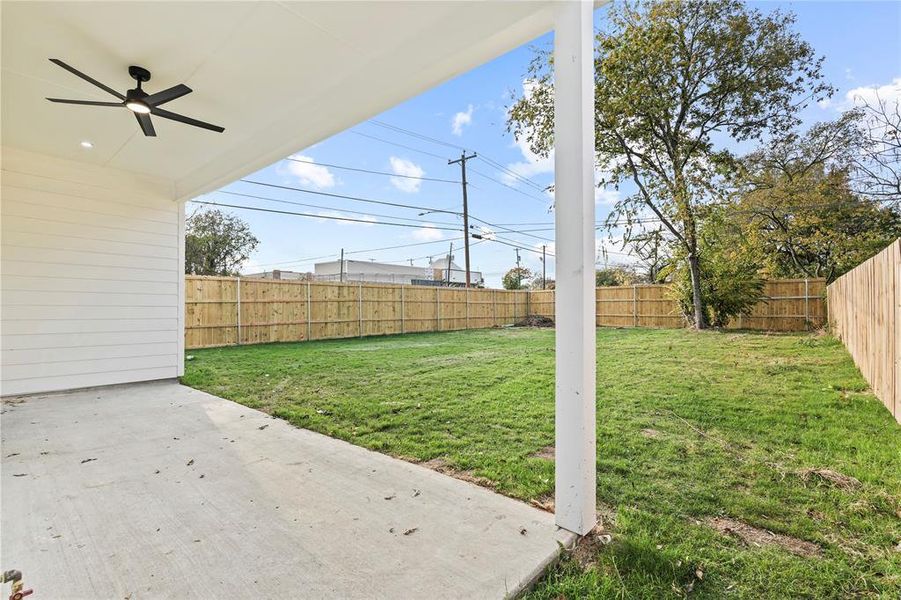Fenced backyard featuring ceiling fan and a patio area