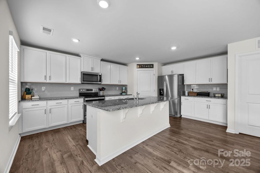 36” birch cabinets with crown molding, sleek granite countertops, and island seating in the kitchen.