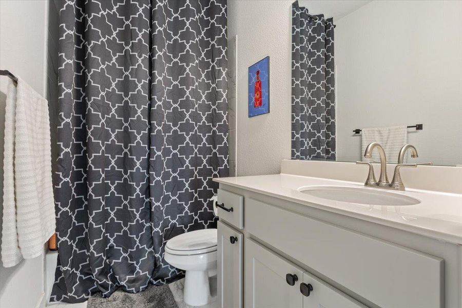 Full bathroom featuring vanity, a textured wall, and shower / tub combo with curtain