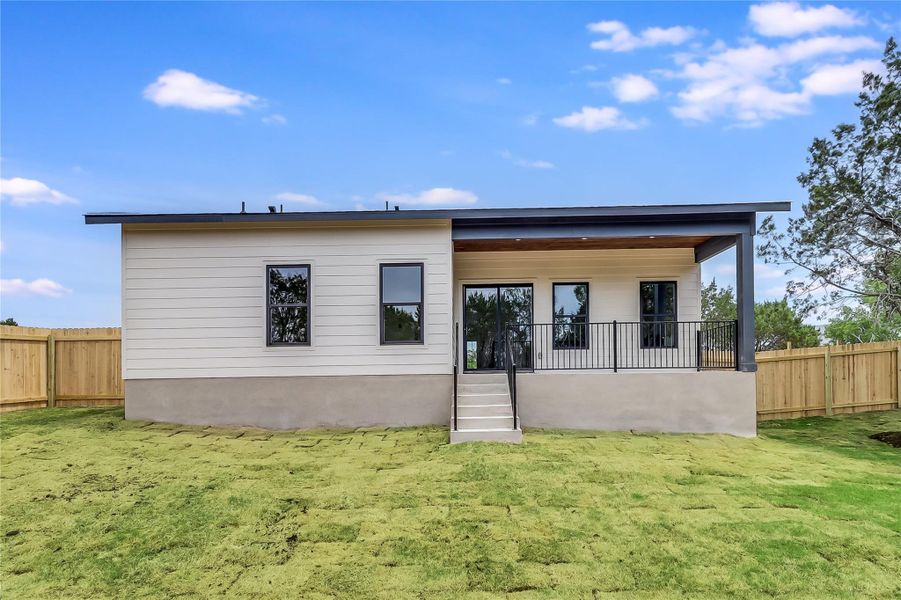 Back of house with a yard and a fenced backyard