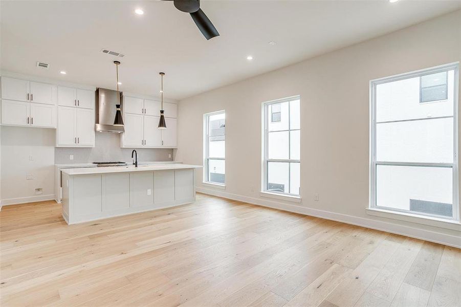 The open kitchen is bathed in natural light from large windows on both sides, creating a bright and welcoming atmosphere.