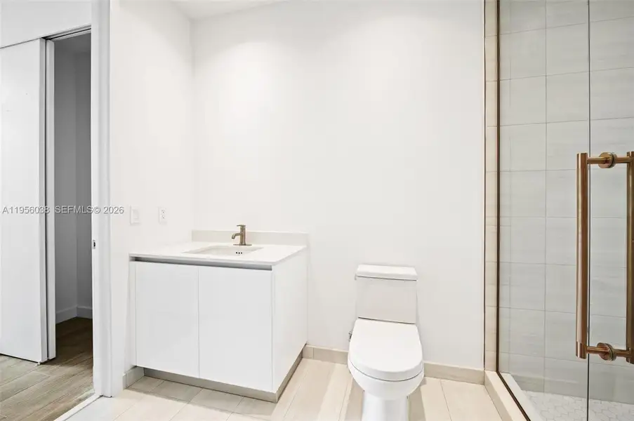 Elegant guest bathroom featuring modern vanity, quartz countertop, brass fixtures, and glass-enclosed shower with designer tile finishes.