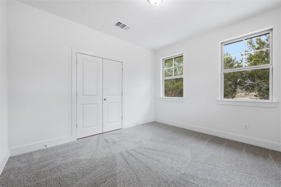 Unfurnished bedroom with light carpet and a closet