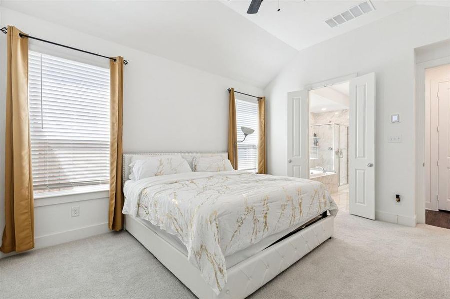 Bedroom featuring light colored carpet, vaulted ceiling, and a ceiling fan Bedroom featuring light colored carpet, vaulted ceiling, and a ceiling fan