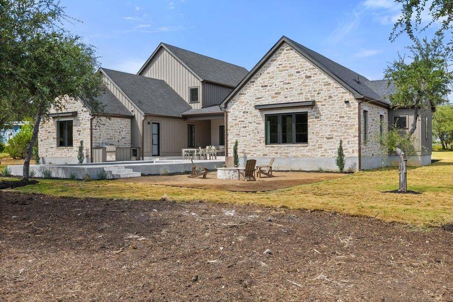 A spacious exterior showcasing elegant stone and siding, complemented by an inviting patio area with a fire pit.
