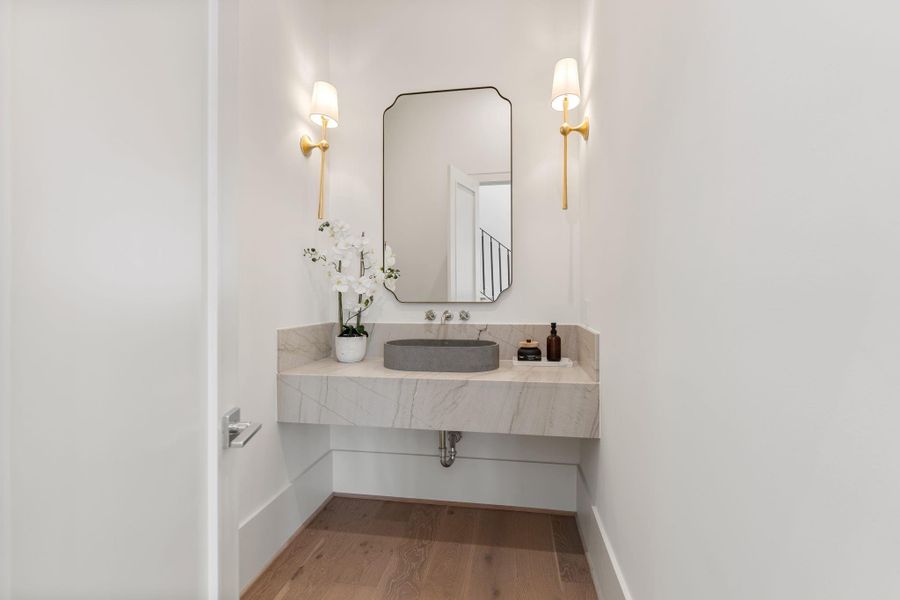 A sleek powder bath offers a refined design with a floating quartzite vanity, modern fixtures, and elevated finishes that reflect the home’s attention to detail.