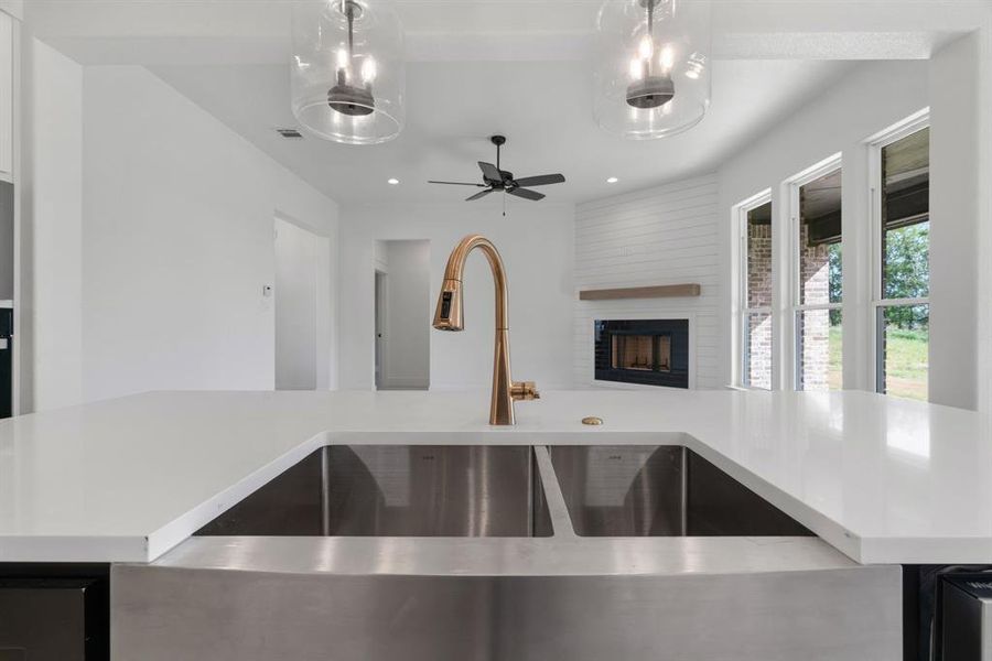 Kitchen with recessed lighting, light countertops, a kitchen island with sink, white cabinets, and hanging light fixtures