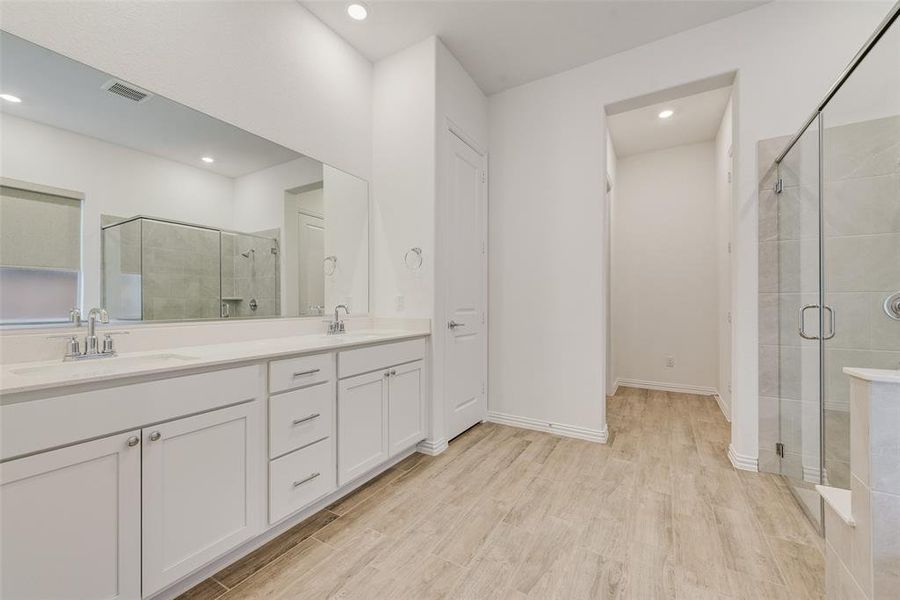 Bathroom featuring a shower stall, double vanity, wood finished floors, and recessed lighting Bathroom featuring a shower stall, double vanity, wood finished floors, and recessed lighting