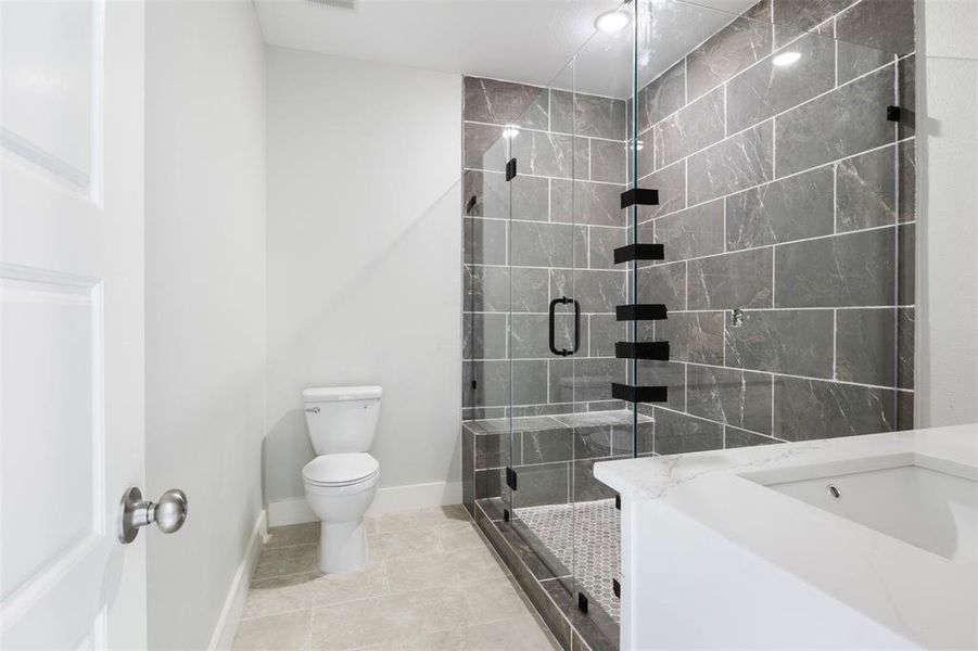 Bathroom featuring a shower with door, tile flooring, and toilet