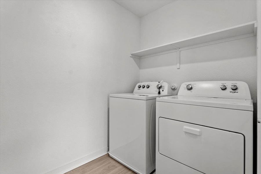 A well-appointed laundry room features modern appliances and convenient overhead shelving.