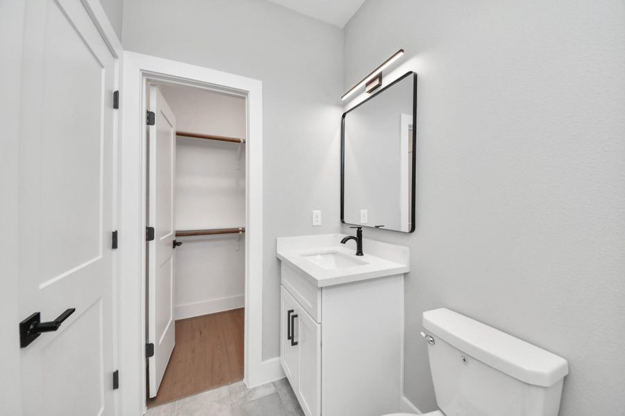 Stylish guest bathroom featuring modern fixtures, quartz countertops, & sleek marble-look tile surround for a clean contemporary feel.