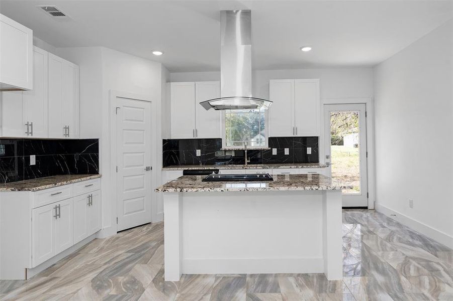 Kitchen featuring white cabinets, decorative backsplash, light stone countertops, and island exhaust hood