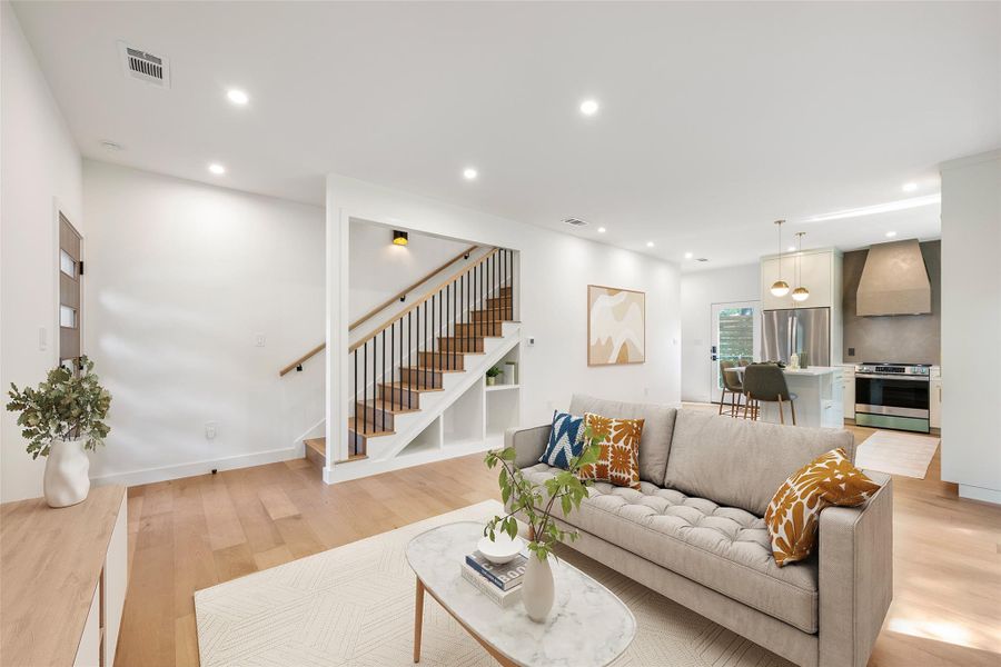Hardwood floors and recessed lighting elevate this open concept living space with a gourmet kitchen nearby. Hardwood floors and recessed lighting elevate this open concept living space with a gourmet kitchen nearby.