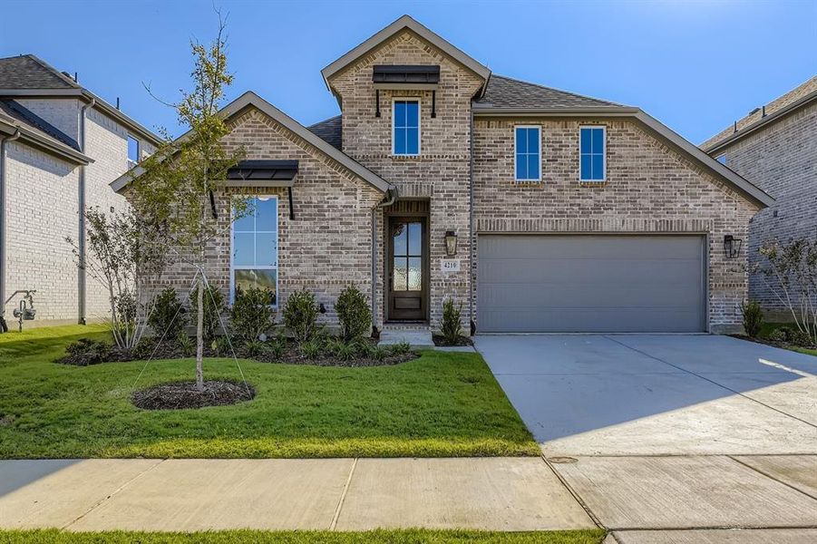 French provincial home featuring brick siding, driveway, a garage, a shingled roof, and a front lawn French provincial home featuring brick siding, driveway, a garage, a shingled roof, and a front lawn