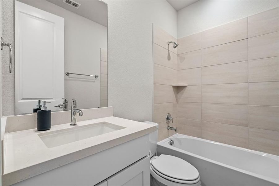 Full bathroom featuring vanity, toilet, and tiled shower / bath