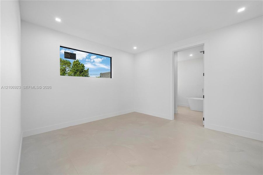 Interior room featuring recessed ceiling lighting, large-format tile flooring, and a horizontal window with a black frame Interior room featuring recessed ceiling lighting, large-format tile flooring, and a horizontal window with a black frame