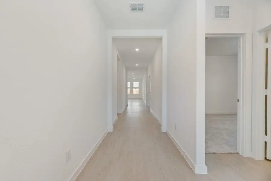 Hallway with light wood finished floors and recessed lighting