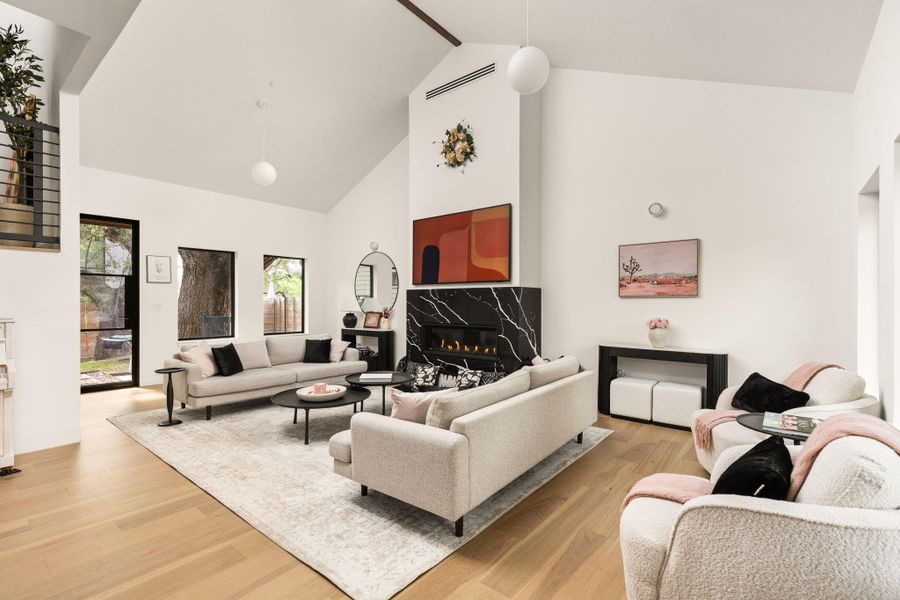 Vast vaulted ceilings complement an elegant fireplace with marble surround, creating an inviting living area. Vast vaulted ceilings complement an elegant fireplace with marble surround, creating an inviting living area.