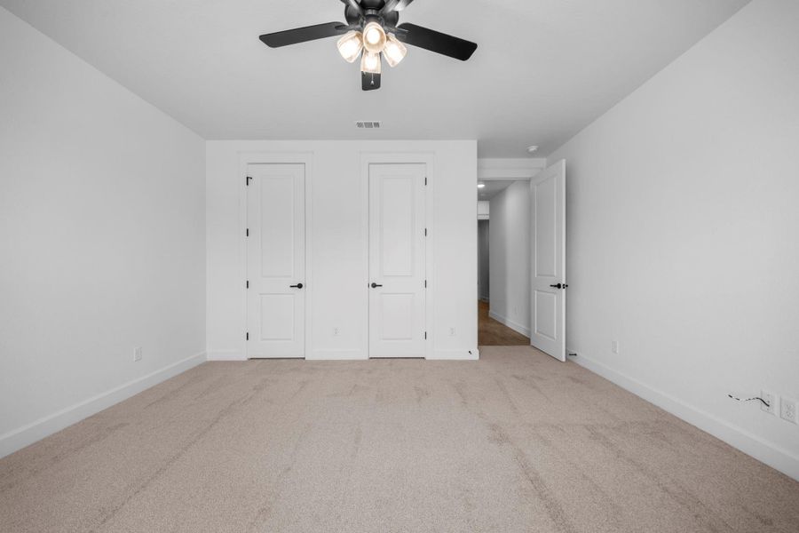 Unfurnished bedroom with two closets, carpet flooring, and ceiling fan