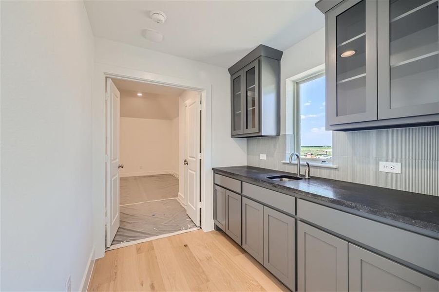 Kitchen featuring gray cabinets, sink, decorative backsplash, and light wood-type flooring