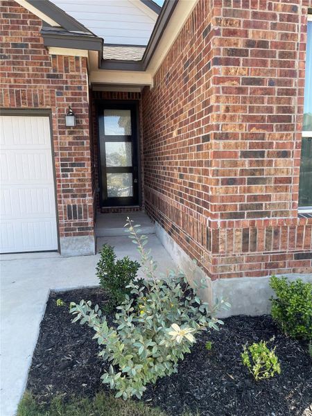 View of exterior entry featuring brick siding and an attached garage View of exterior entry featuring brick siding and an attached garage