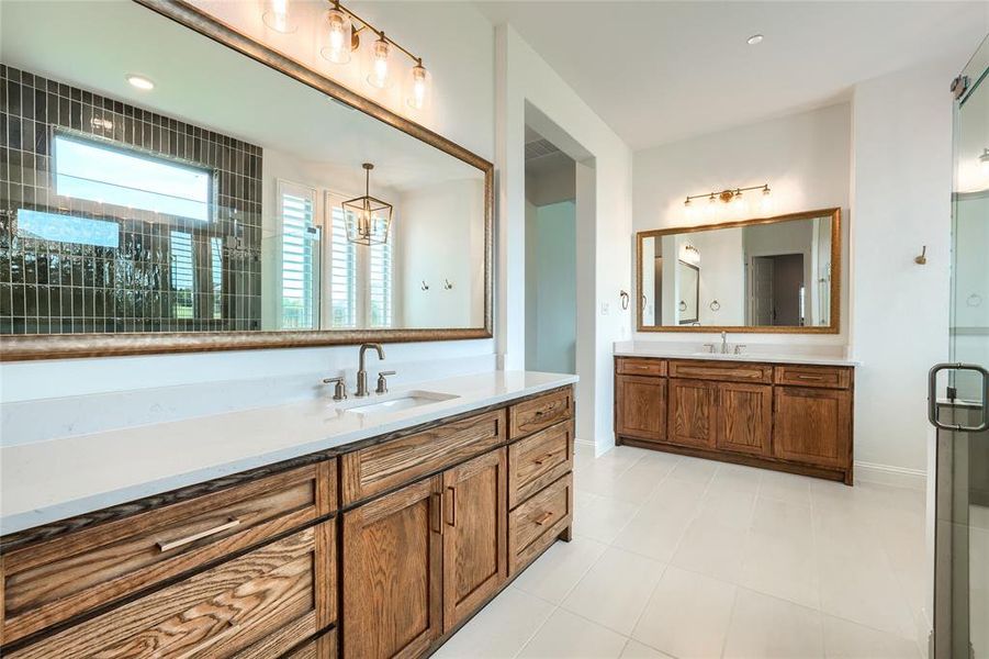 Full bath featuring two vanities, a shower stall, light tile patterned flooring, and recessed lighting