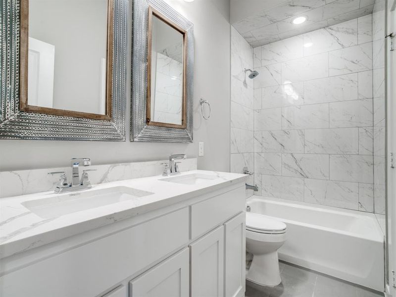 Full bath with double vanity, toilet, washtub / shower combination, and a sink