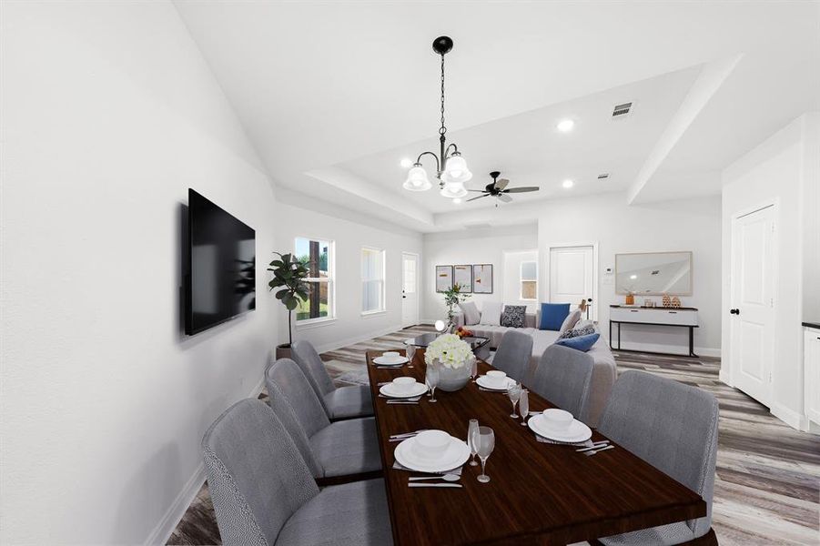 Dining area featuring wood finished floors, a raised ceiling, a chandelier, ceiling fan, and recessed lighting Dining area featuring wood finished floors, a raised ceiling, a chandelier, ceiling fan, and recessed lighting