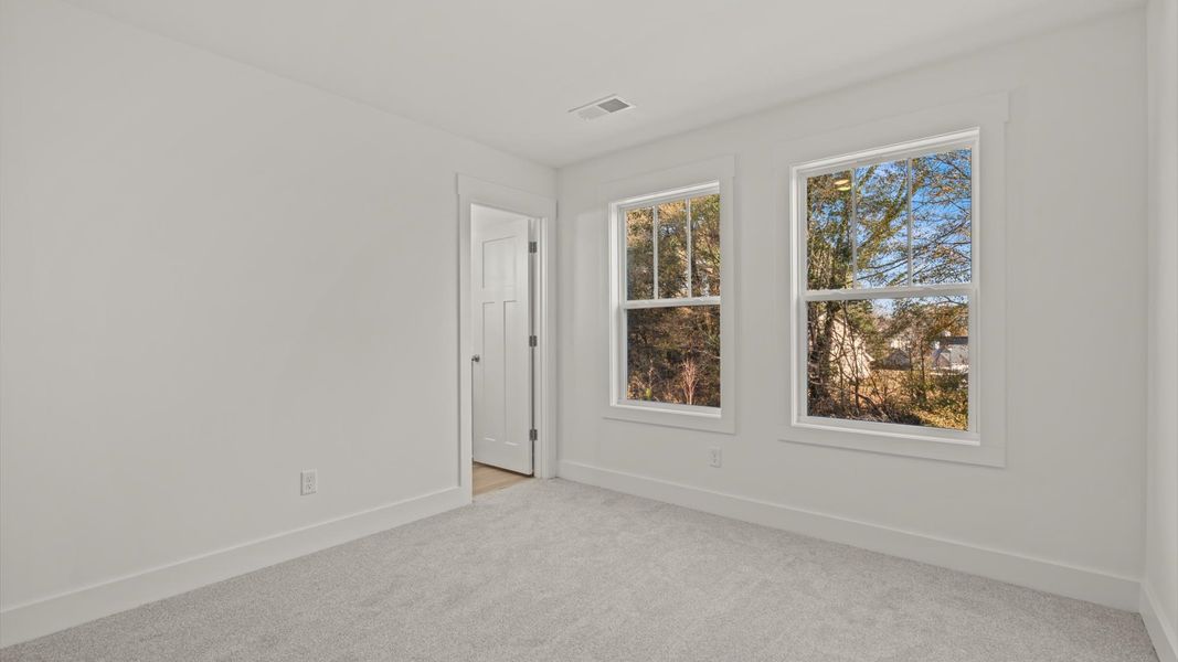 Bright and serene bedroom with comfortable carpeted flooring and large windows for vibrant light