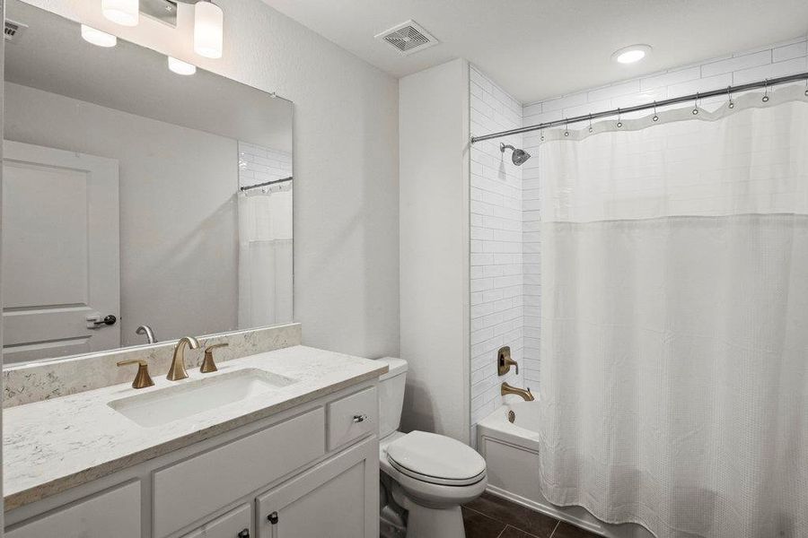 Bathroom with visible vents, shower / bath combo with shower curtain, toilet, tile patterned flooring, and vanity