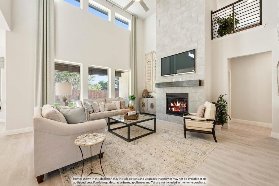 Living room with two-story ceiling, stone fireplace, neutral sofas, and hardwood floors