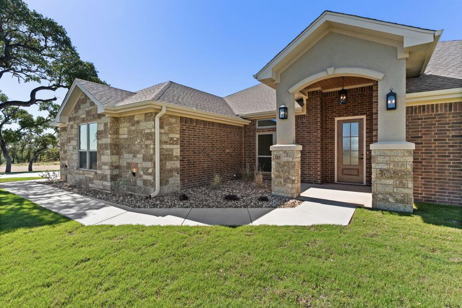 View of front of home with roof with shingles, a front yard, brick siding, and a porch View of front of home with roof with shingles, a front yard, brick siding, and a porch