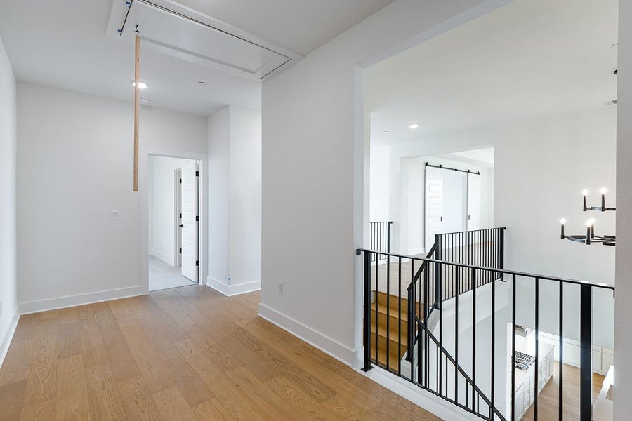Corridor featuring light wood-style flooring, an upstairs landing, and recessed lighting