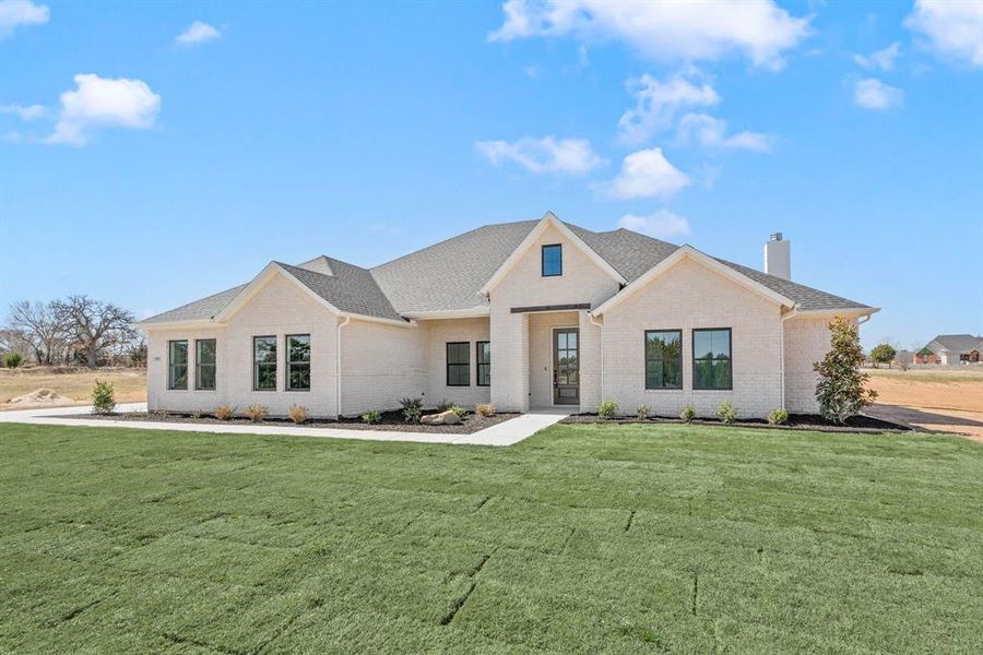 Modern inspired farmhouse featuring brick siding, a front lawn, a chimney, and a shingled roof