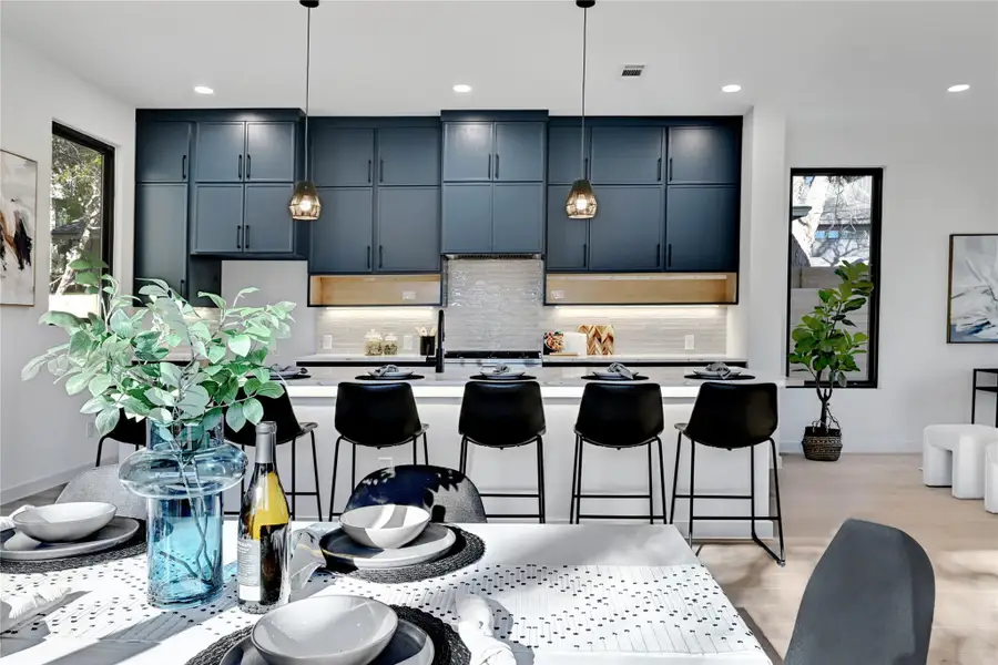 Kitchen featuring a breakfast bar, light countertops, a kitchen island with sink, and tasteful backsplash