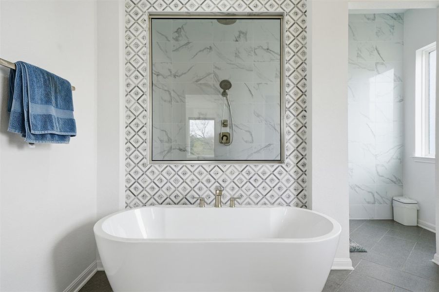 Contemporary bathroom featuring a white freestanding soaking tub, a tiled shower with a glass enclosure, and modern gray floor tiles
