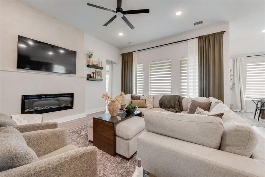Living space featuring a built-in linear electric fireplace, recessed lighting, and a ceiling fan