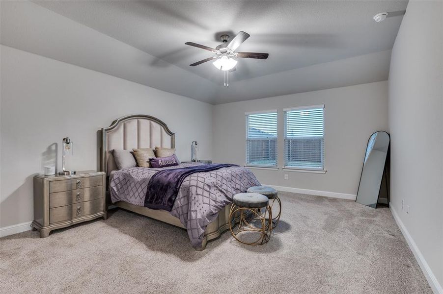 Bedroom featuring light carpet, lofted ceiling, and a ceiling fan