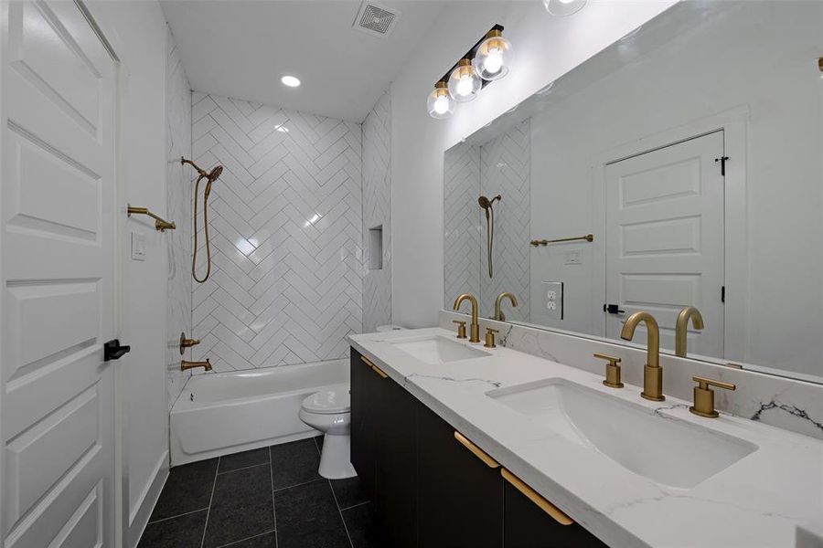 The third bath features two sinks with brushed brass fixtures and a tub and shower combo. There is plenty of storage for your bathroom supplies.