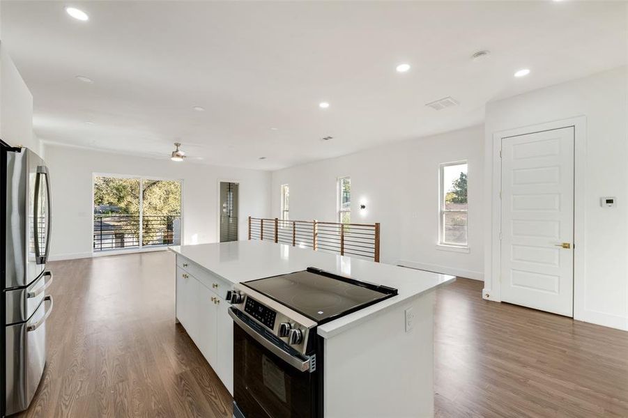 Kitchen featuring electric range oven, white cabinetry, freestanding refrigerator, dark wood-style floors, and recessed lighting Kitchen featuring electric range oven, white cabinetry, freestanding refrigerator, dark wood-style floors, and recessed lighting