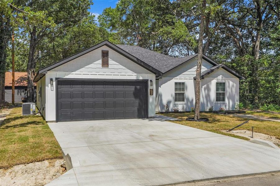 White siding exterior with a dark shingle roof and a dark paneled garage door White siding exterior with a dark shingle roof and a dark paneled garage door