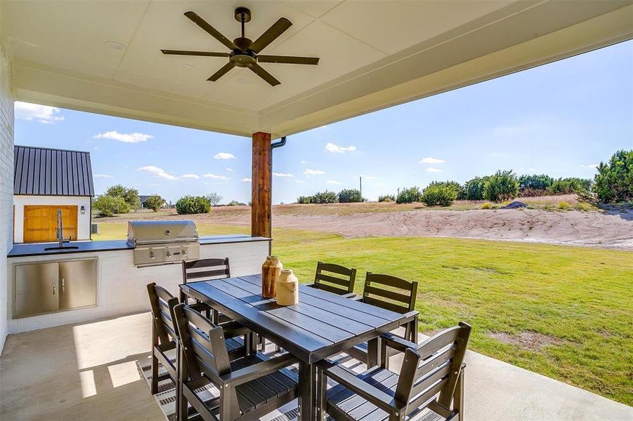 View of patio / terrace featuring area for grilling, an outdoor kitchen, a rural view, sink, and ceiling fan