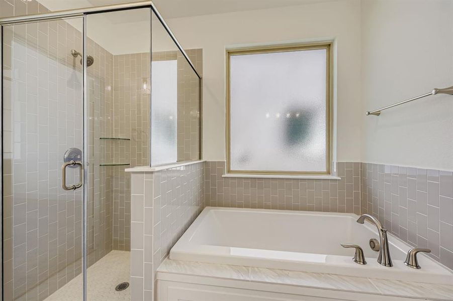 Bathroom featuring a bath, healthy amount of natural light, and a stall shower Bathroom featuring a bath, healthy amount of natural light, and a stall shower