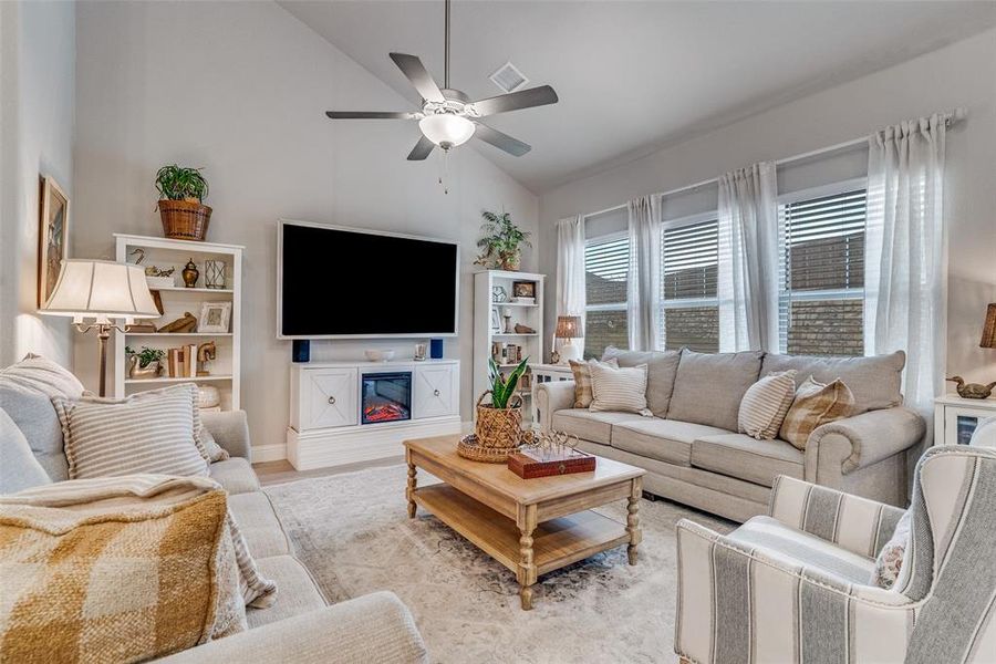 Living area featuring a ceiling fan, high vaulted ceiling, and wood finished floors Living area featuring a ceiling fan, high vaulted ceiling, and wood finished floors