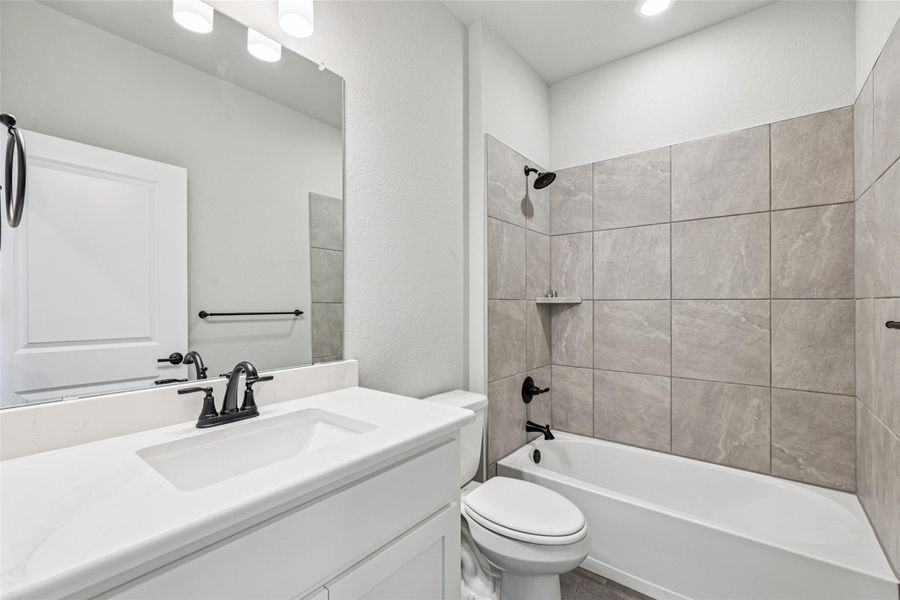 Full bathroom with toilet, vanity, and shower / tub combination Full bathroom with toilet, vanity, and shower / tub combination